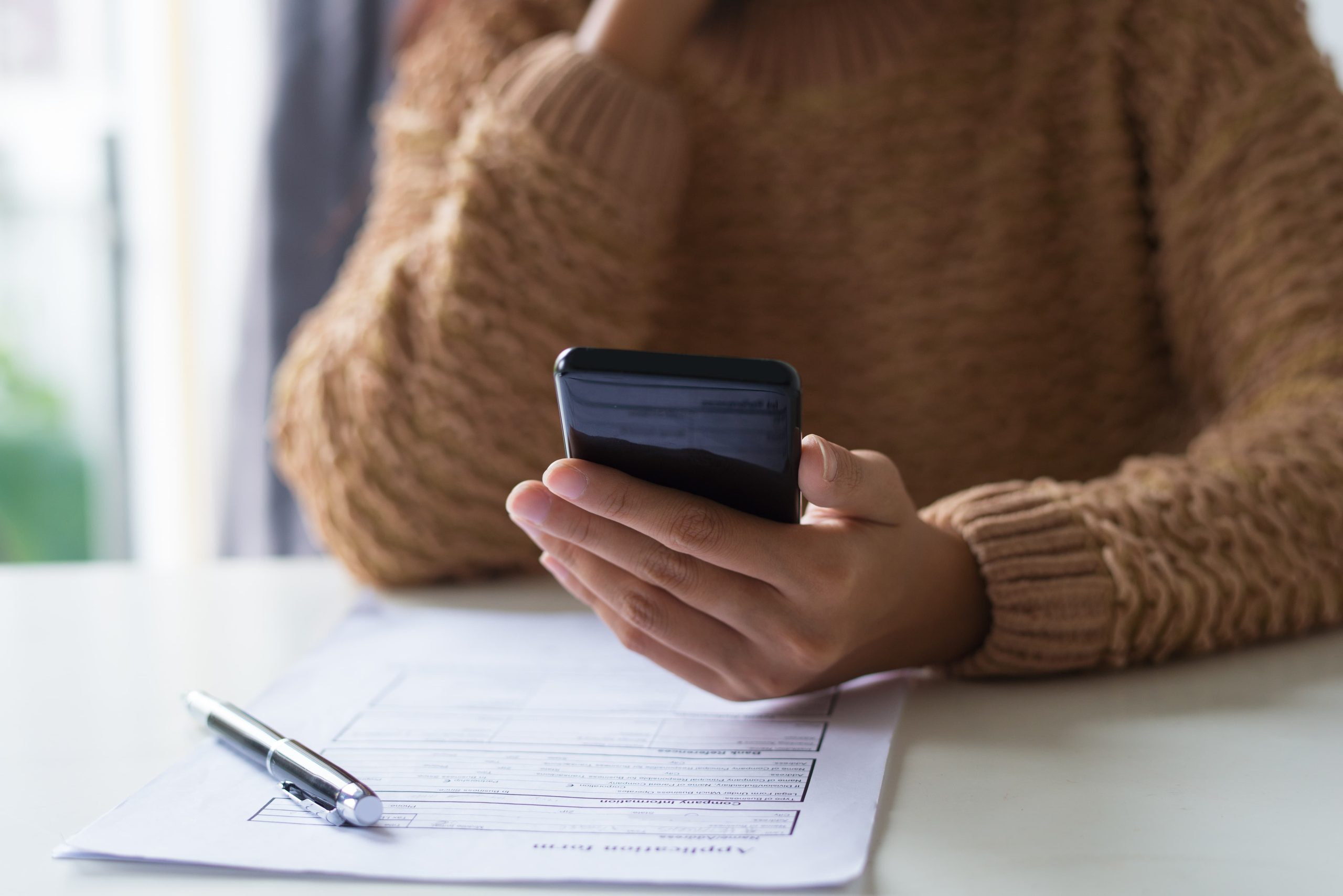 close up busy lady filling document checking sms phone scaled