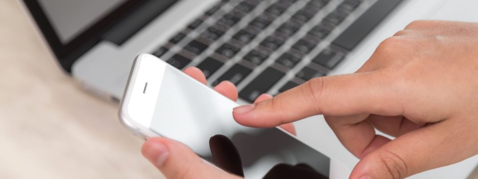 person touching phone with laptop background scaled