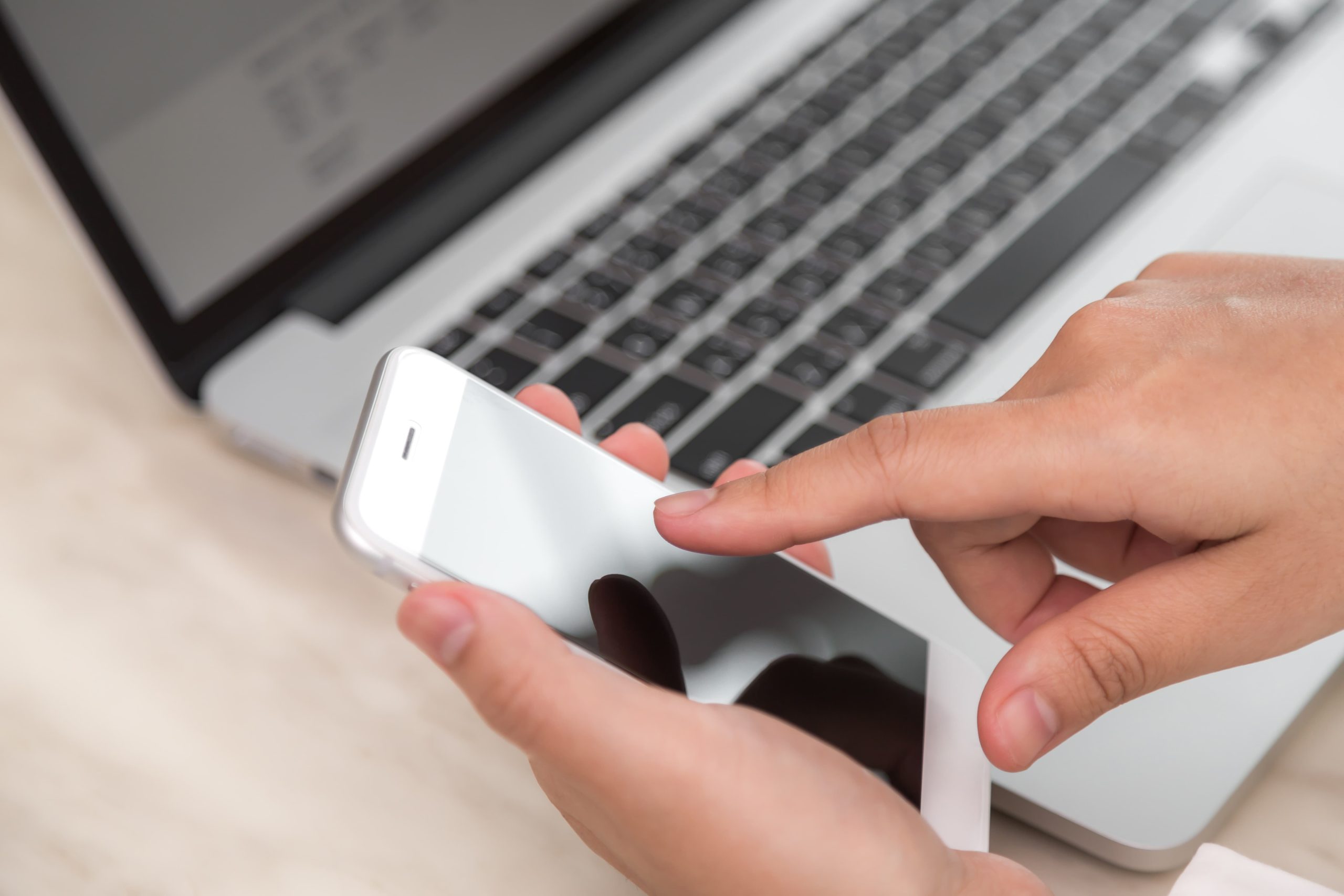 person touching phone with laptop background scaled